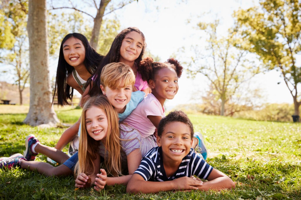 Multi-ethnic group of kids lying on each other in a park
