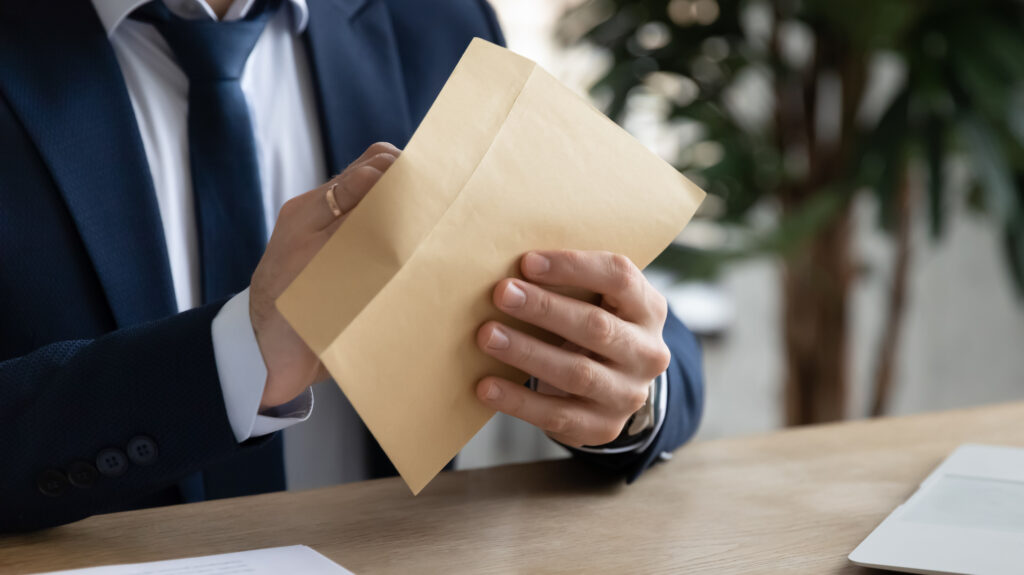 Man in formal attire opening an envelope