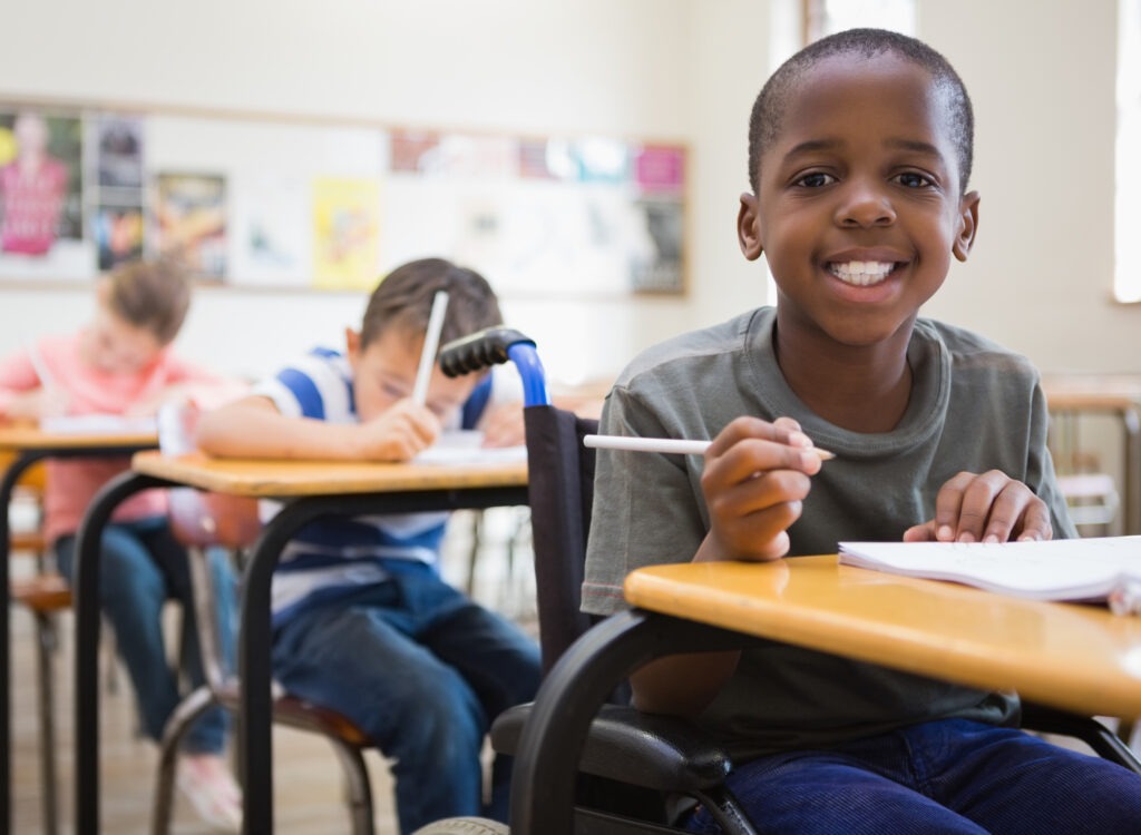 Disabled pupil smiling at camera in classroom