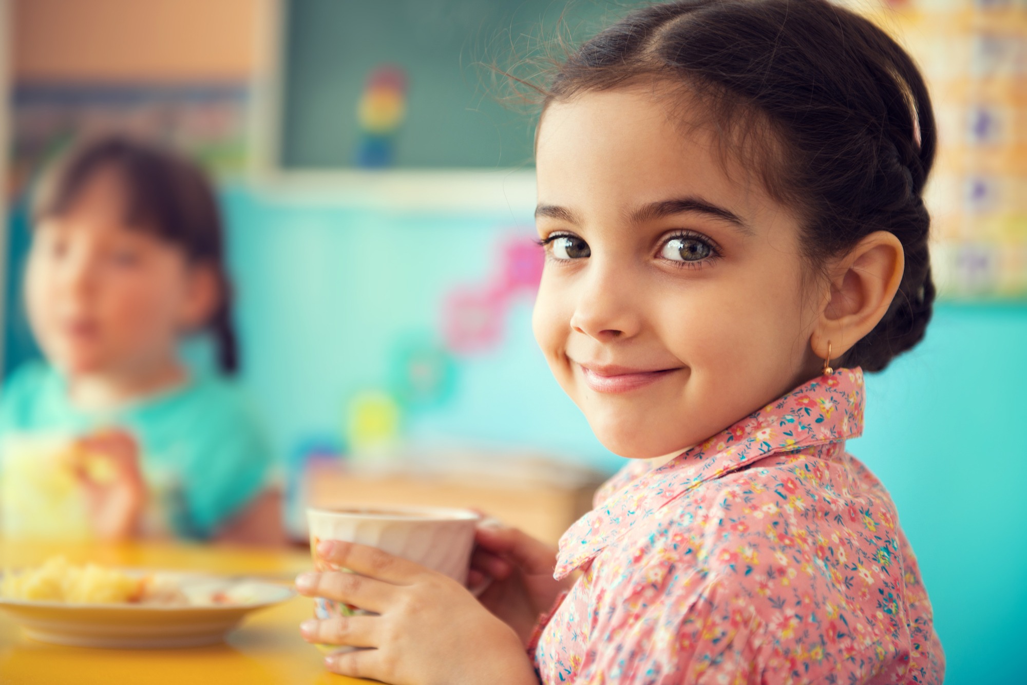 Cute little hispanic girl drinking milk at school