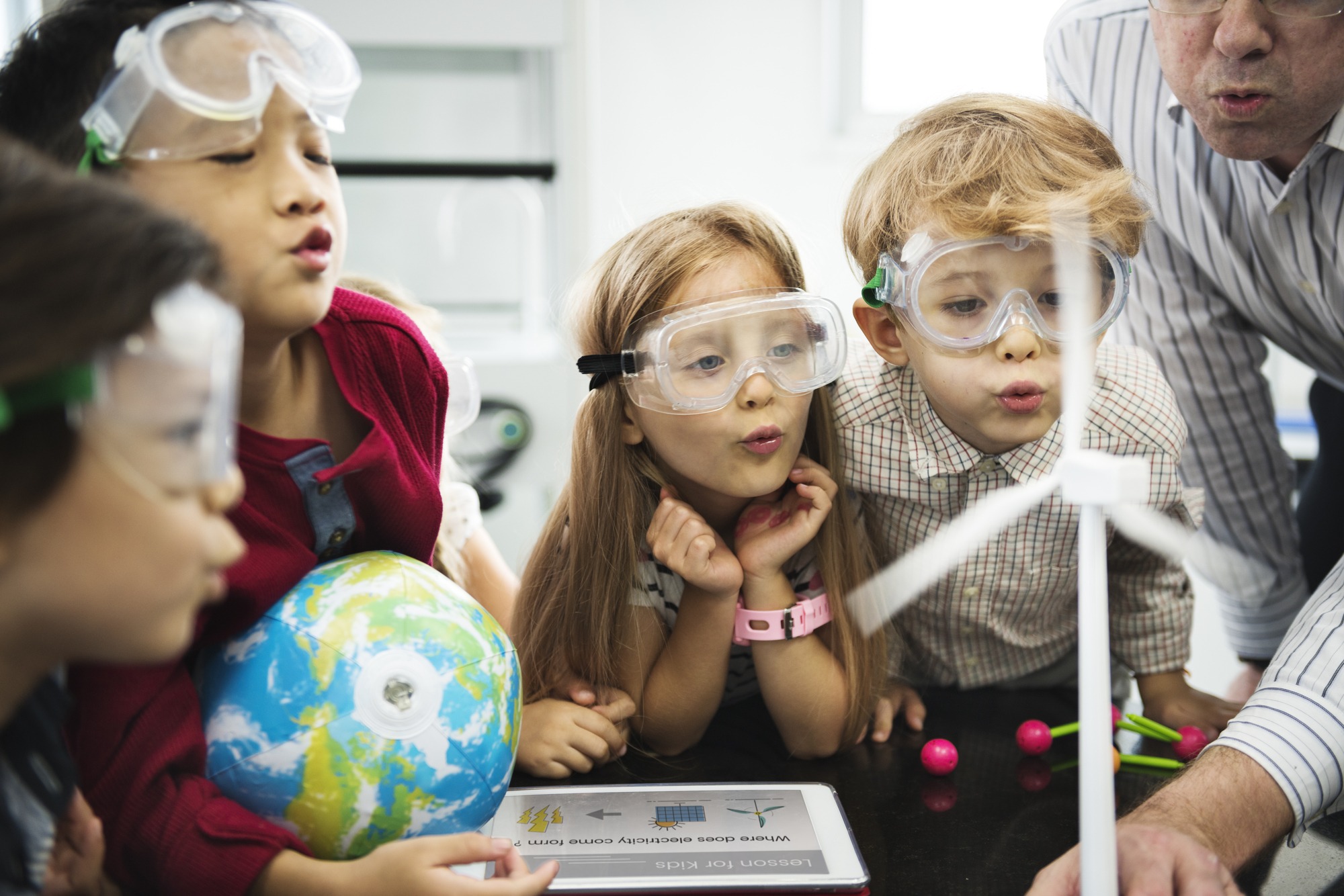 Diverse kindergarten students learning energy producer from solar windmill in science class